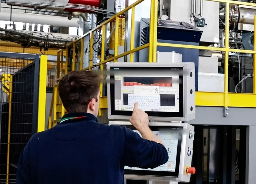 Operador ajustando sistema de controle em célula industrial